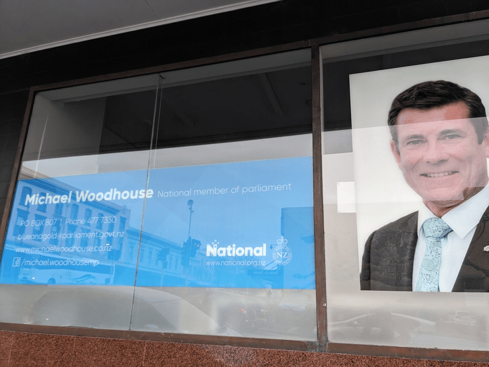 a dark building with a big whoto of national MP michael woodhouse on the side and National party branding