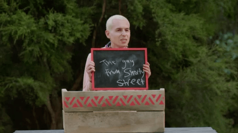 a young man holds a chalkboard up in front of him