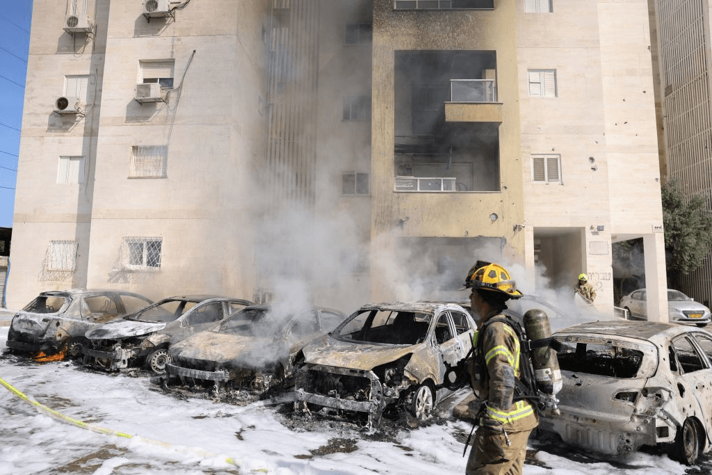 Israeli fire fighters douse the blaze in a partking lot outside a residential building following a rocket attack from the Gaza Strip in the southern Israeli city of Ashkelon. (Photo by AHMAD GHARABLI/AFP via Getty Images) 
