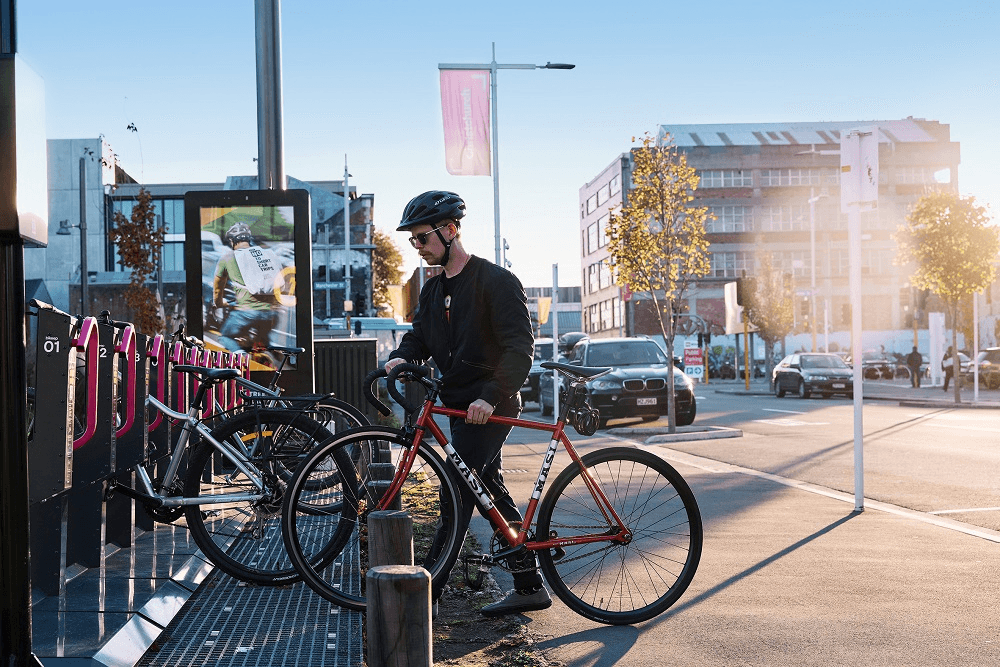 a man putting a bike in a ping steel cage to lock it on a sunny morning