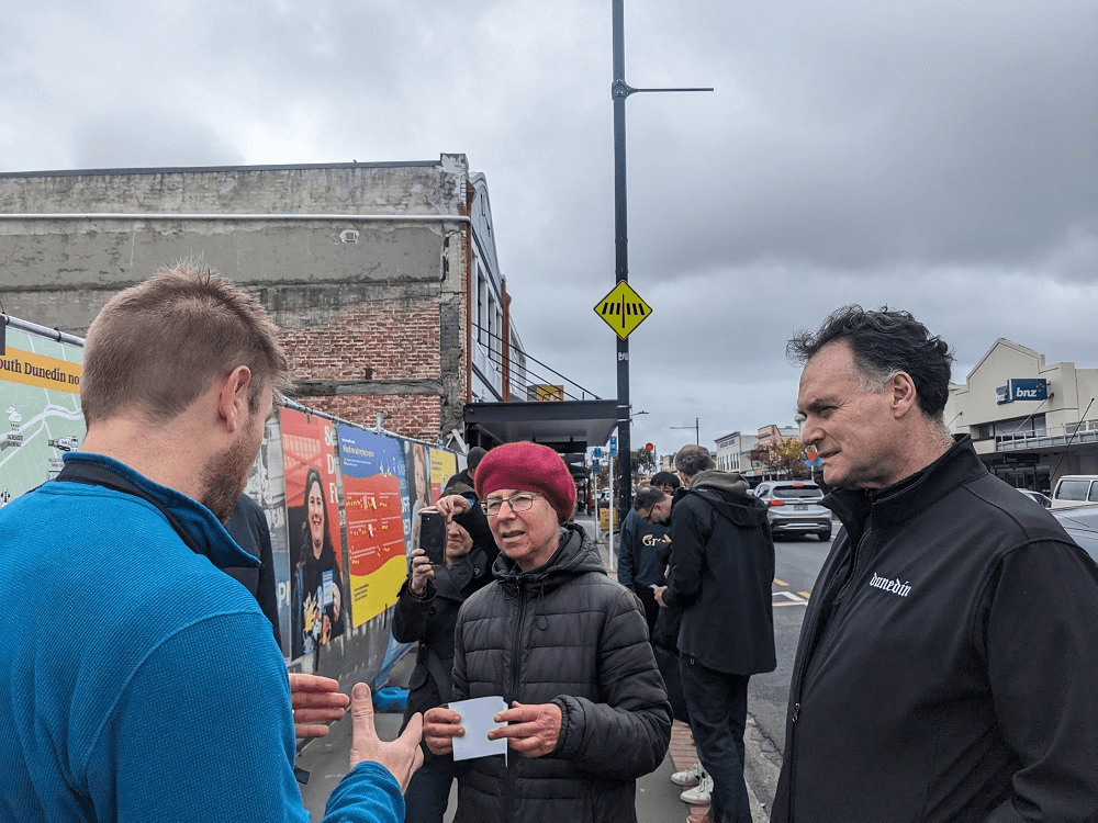 people talking to a man in a black jacket and a man in a blue jacket with their backs to the camera