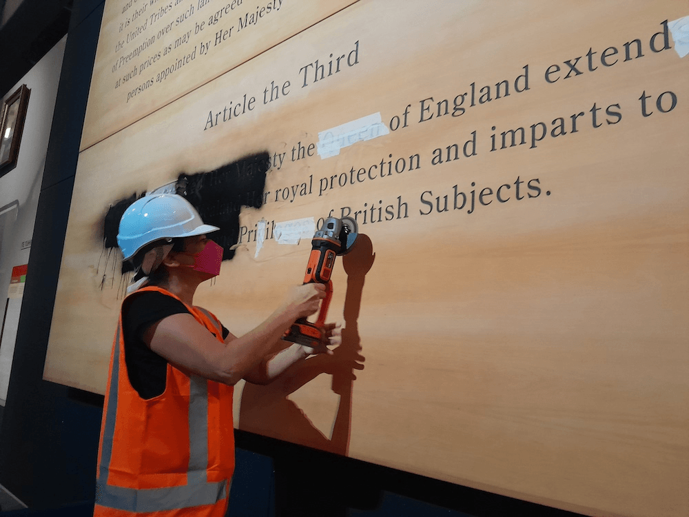 A protestor takes to that exhibit with an angle grinder.