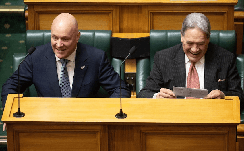 two men sitting on parliament chairs chuckling