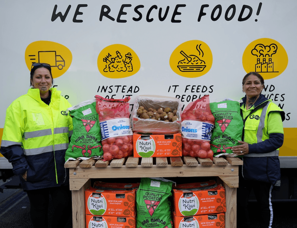 two smiling women iwth moko kauae and big packets of food saying 'we rescue food'