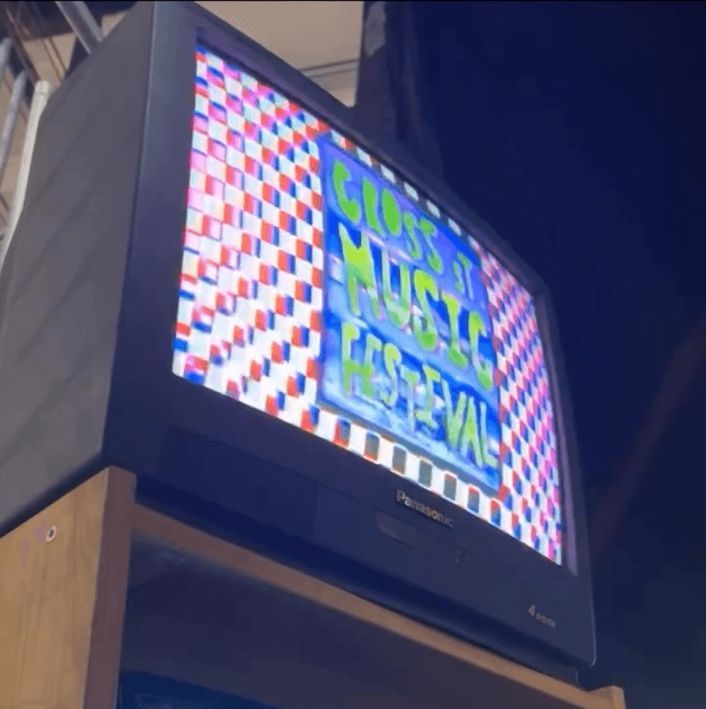 One of the vintage TVs with a trippy Cross Street Music Festival logo on a multi-coloured background.