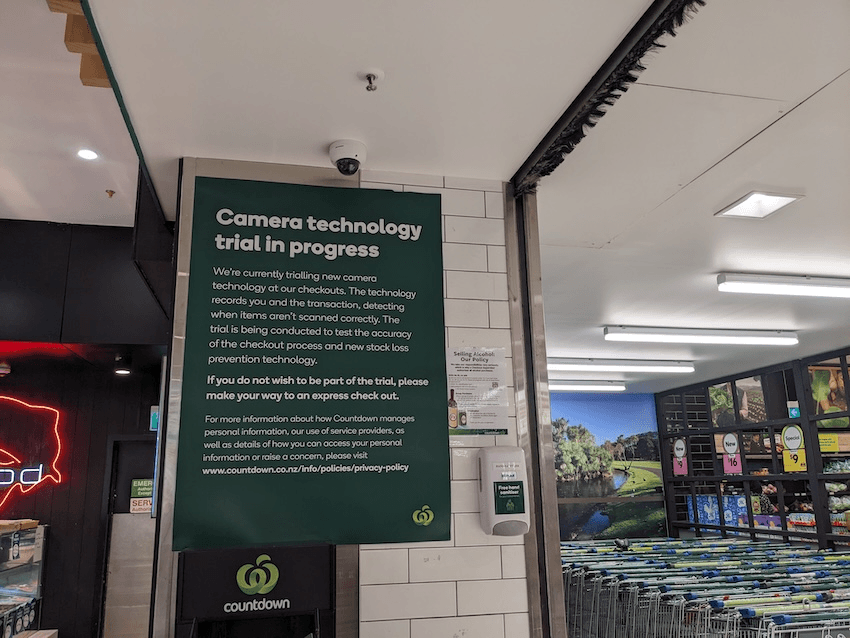 a sign at a supermarket informing people that there is a camera trial at the self service checkout