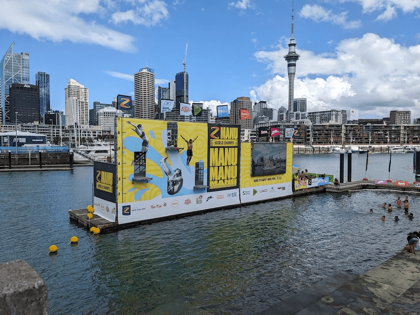 a competitor jumps with their arms flung out, the sky tower in the background