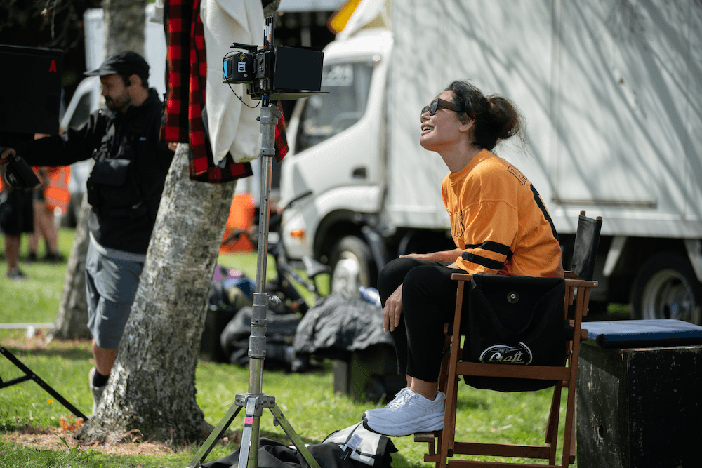 House sits on her director's seat on-set.