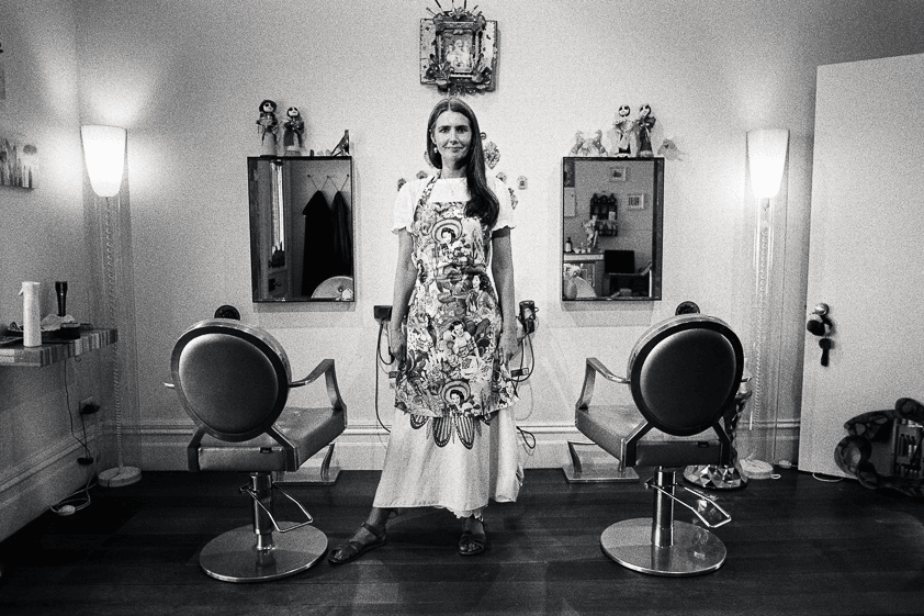 A hairdresser stands in her salon in a black and white photo