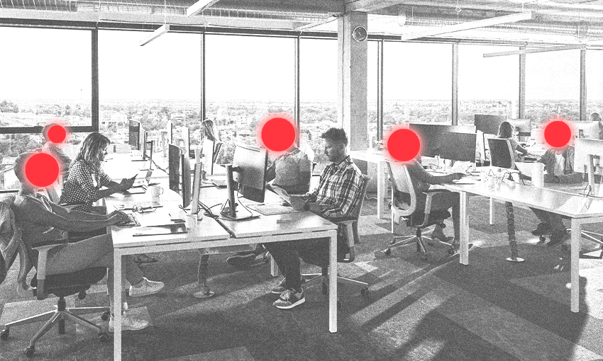 A group of people sit at desks in an office. Some red dots are placed over half the faces to signal they're being removed