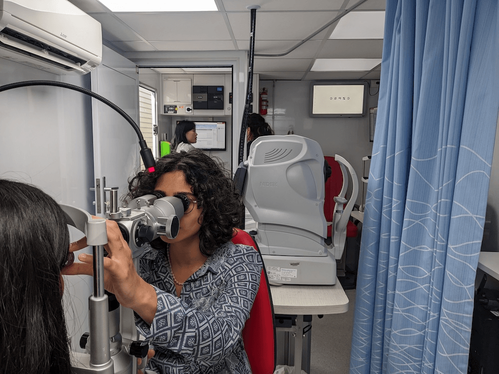 a woman with a blue shirt looking through a pair of glasses into someone's eye