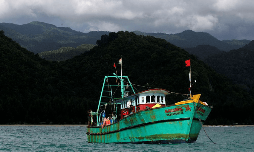 a green boat under a stormy sky with hills in the backgroun