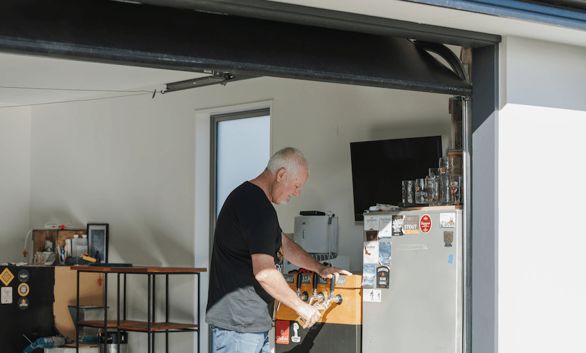 Craig Herron fills a bottle up with home brewed beer in his garage.