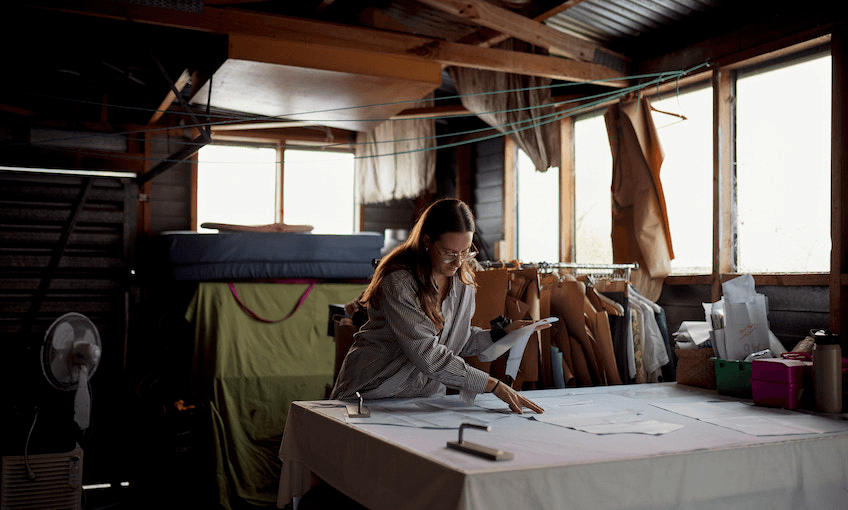 Whitney Barnes works at her cutting table to cut out bits of fabric in her garage.