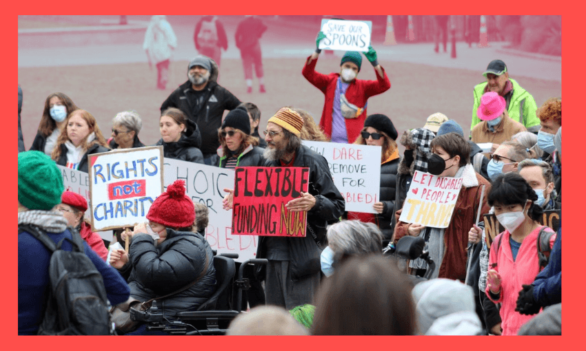 a group of people hold signs protesting disability cuts with humorous slogans, the background is faded out and there isa red border around the image