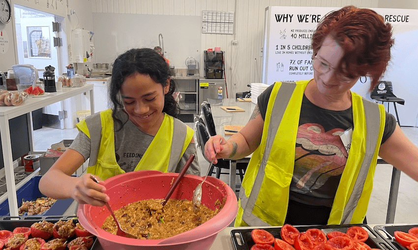 Fair Food head chef Adele at right works in a busy kitchen and a volunteer to her left assists. They are making a stuffed tomato dish.