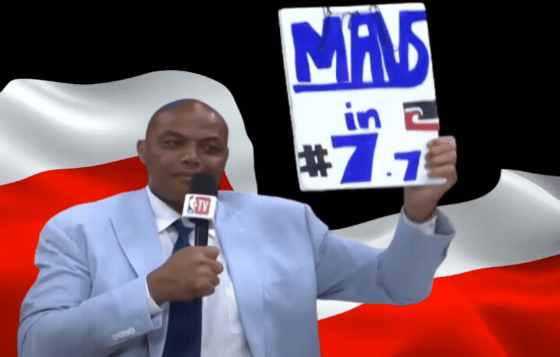Charles Barkley holds a sign reading: "Mavs in #7.7.," with a Tino Rangatiratanga flag on it and another Tino Rangatiratanga flag as the background.