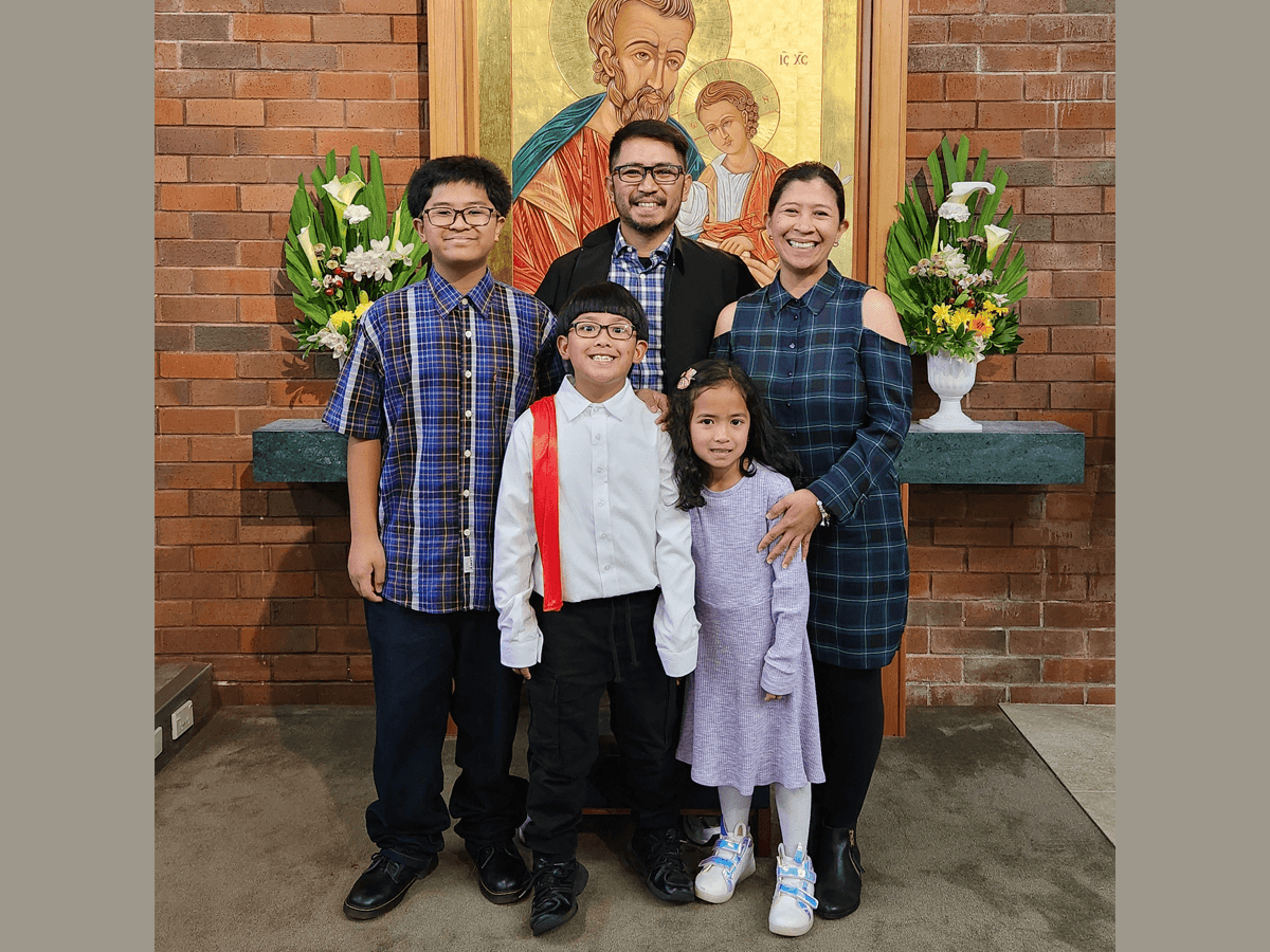 Family of five, standing in front of a religious painting..