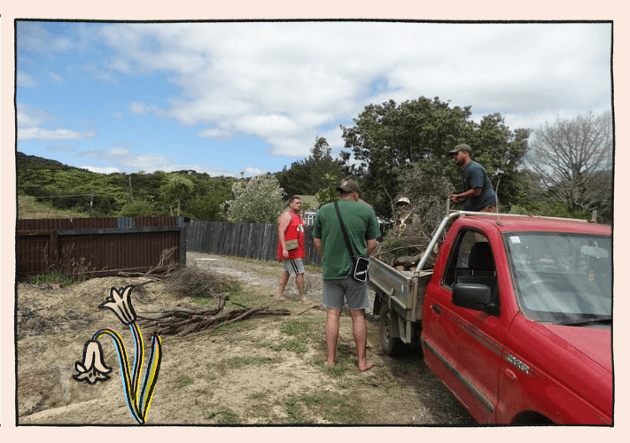 A man unloads wood from a red ute with three men standing around him.