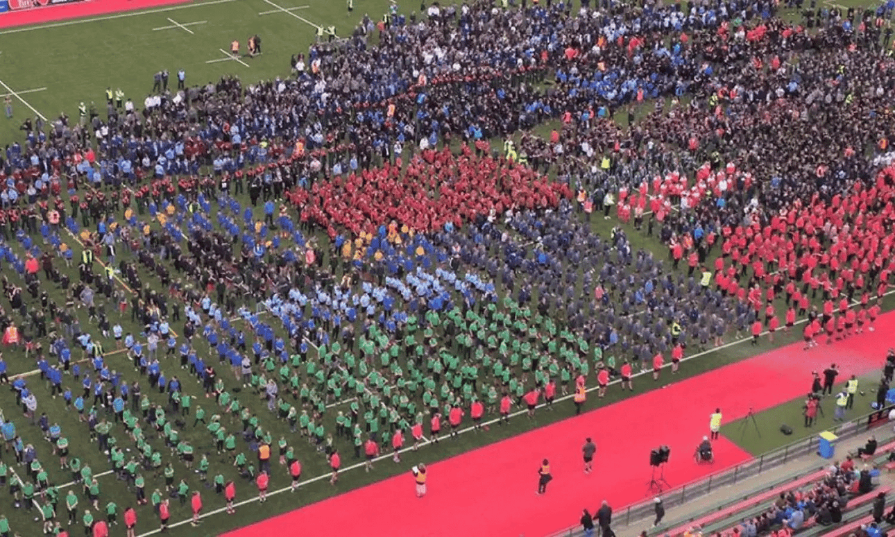 An aerial image of thousands of school children in a stadium.