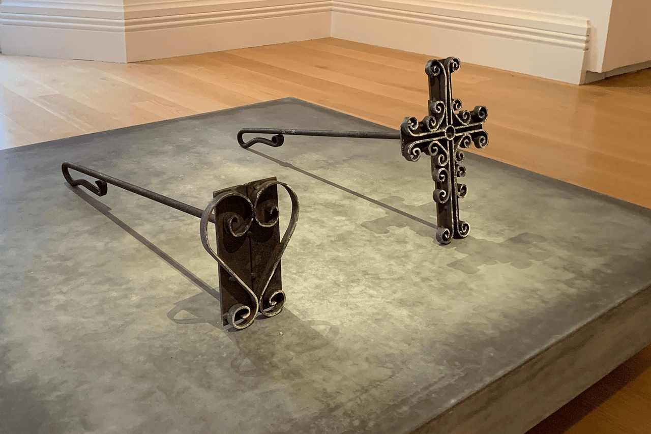 Photo of two wrought iron brands, one in the shape of a heart and the other a christian cross