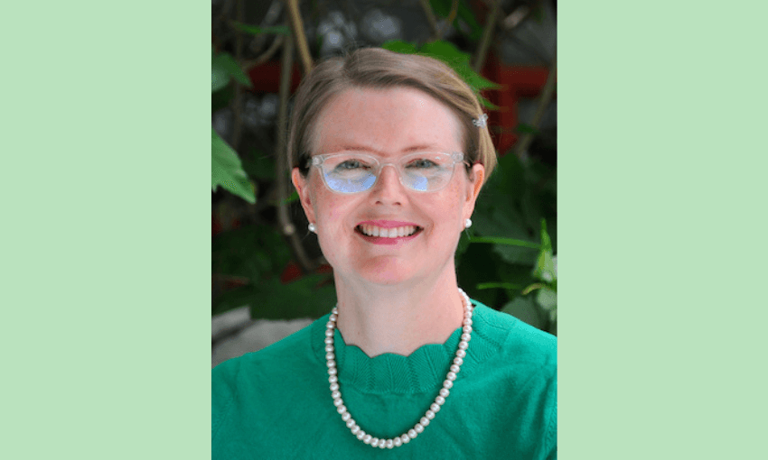 Lucy telfar barnard, a white woman with glasses and short bloneish hair pinned back neatly wearts a green top and pearl necklace against a light green background