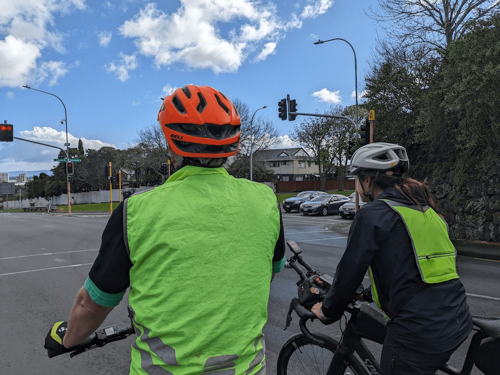 two people in fluro vests at a road intersection with blue skies