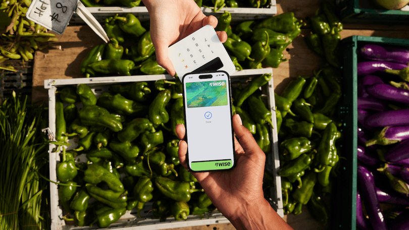 a background of green peppers and someone using the wise app to pay for them