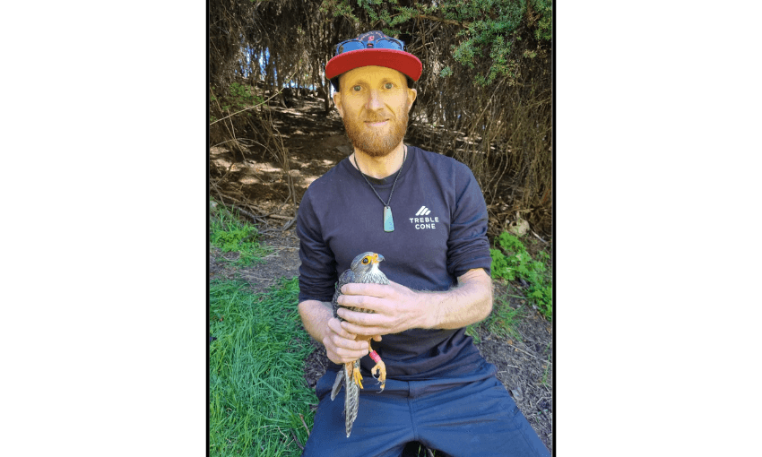 a white man holding a slightly startled looking hawk and wearing a treble cone tshirt