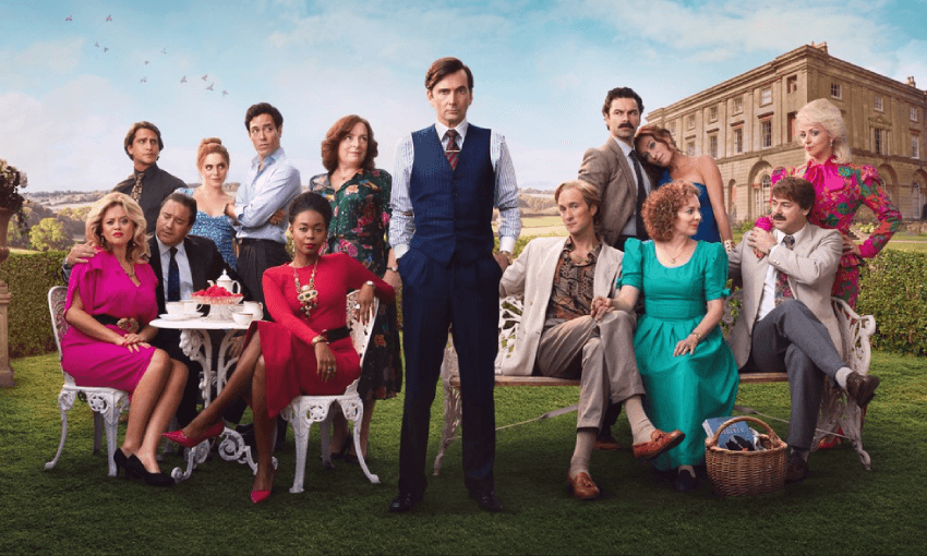 The cast of Disney+’s Rivals in formal attire gather outside a grand estate. They are arranged around ornate garden furniture, with a picnic basket, tea set, and a cake on the table. Front row from left to right: Emily Atack as Sarah Stratton, Rufus Jones as Paul Stratton, Nafessa Williams as Cameron Cook, David Tennant as Lord Tony Baddingham, Oliver Chris as James Vereker, Katherine Parkinson as Lizzie Vereker and Danny Dyer as Freddie Jones. Back row from left to right: Luke Pasqualino as Basil 'Bas' Baddingham, Alex Hassell as Rupert Campbell-Black, Bella Maclean as Agatha ‘Taggie’ O'Hara, Claire Rushbrook as Lady Monica Baddingham, Aidan Turner as Declan O'Hara Victoria Smurfit as Maud O'Hara and Lisa McGrillis as Valerie Jones