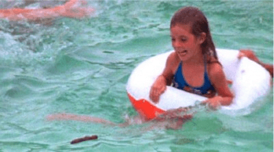 A girl in a floating ring makes a face with a poo floating by in the pool.