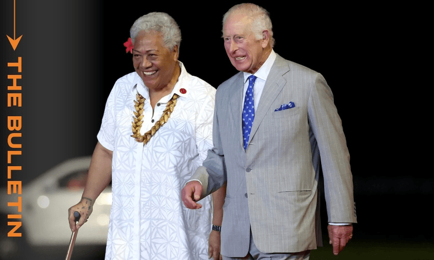 Two people are walking together. One is wearing a white patterned shirt and is prime minister of Samoa Fiame Naomi Mata'afa and the other is King Charles III in a light gray suit with a blue tie.