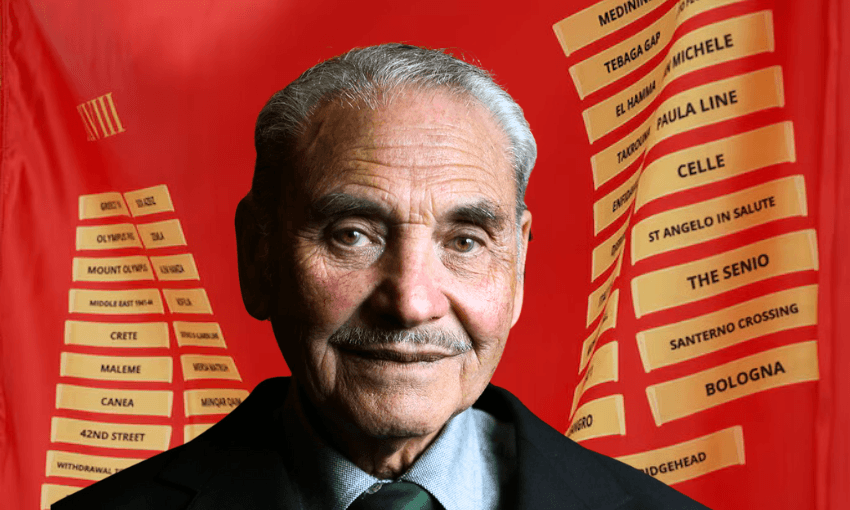 An older man with a moustache and grey hair is smiling slightly in front of a red background with yellow tags listing names of various locations. He wears a dark suit and tie.