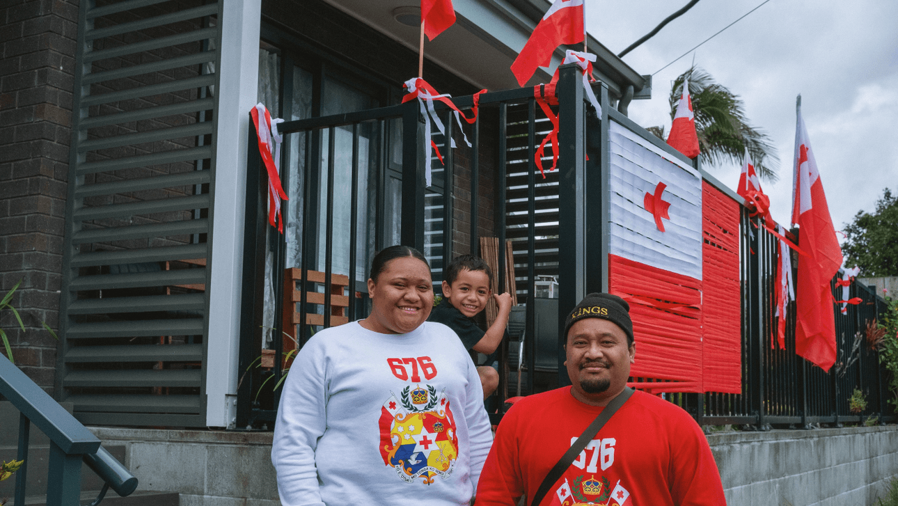 A family of three with Tongan flags on their balcony