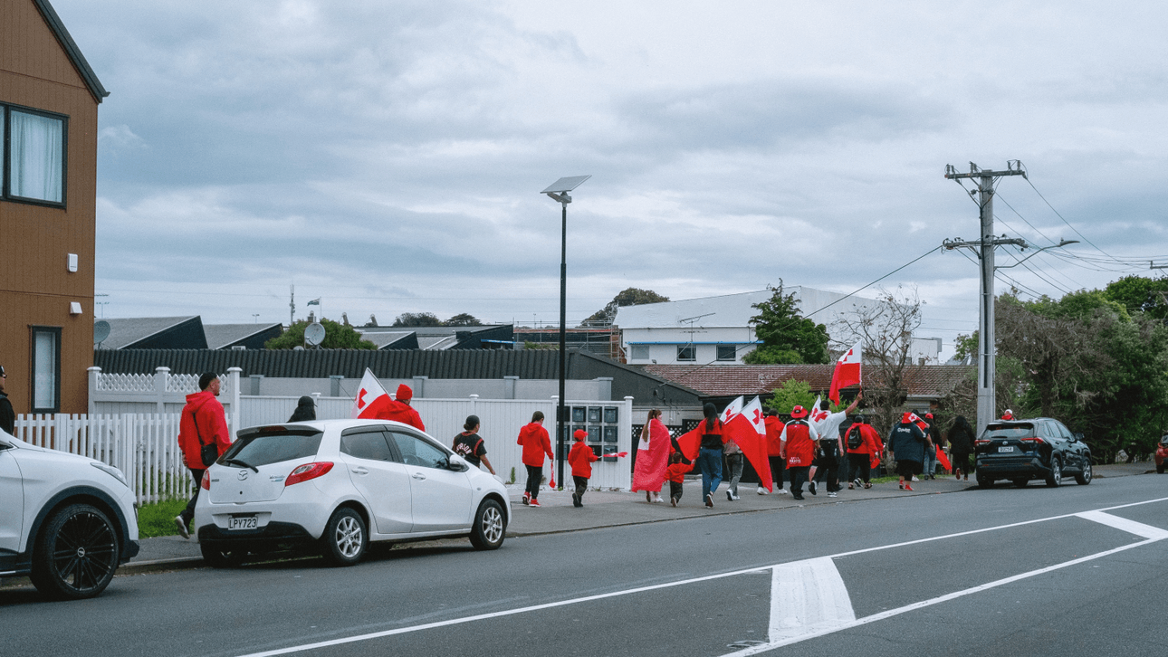 people in red walking down the street with Tongan flags