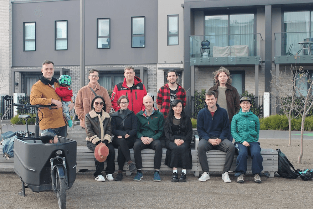 a group of people standing in front of a building with a kid in a cargo bike