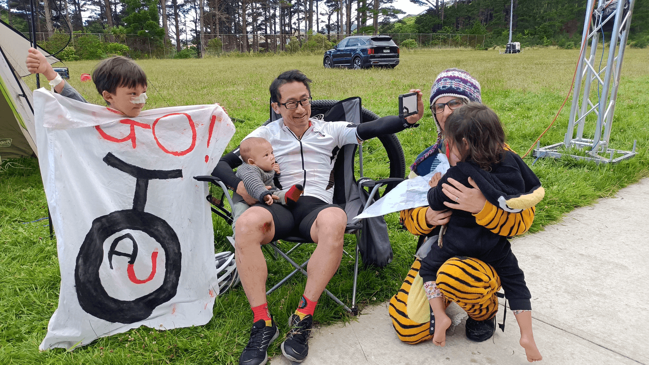 Ken Looi takes a post-world record selfie with his family. He is sitting in a camping chair with his wife and children around him. 