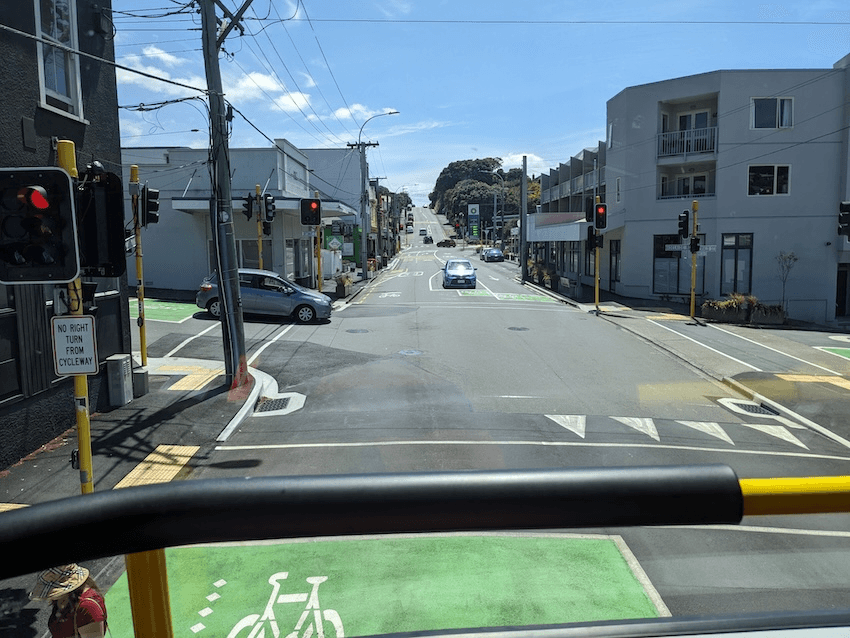 a bus window, with the long, straight road of The Parade stretching out in front of the bus