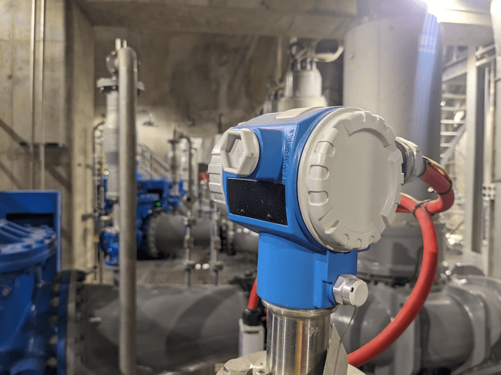 a blue pump in focus surrounded by other pipes lit by artificial light 