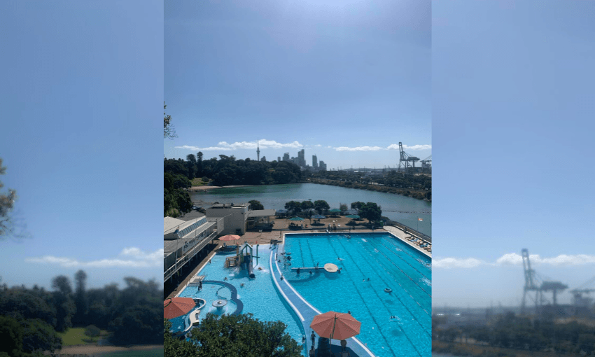 a blurry auckland skyline with a photo of the pool complex in parnell in the centre, the water is radiant, the air is sunny and the darker green of the basin glams in the background