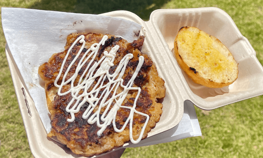 A mussel fritter with fry bread in a biodegradable container held outdoors.