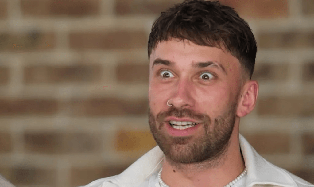A man with brown hair sits stunned with eyes wide