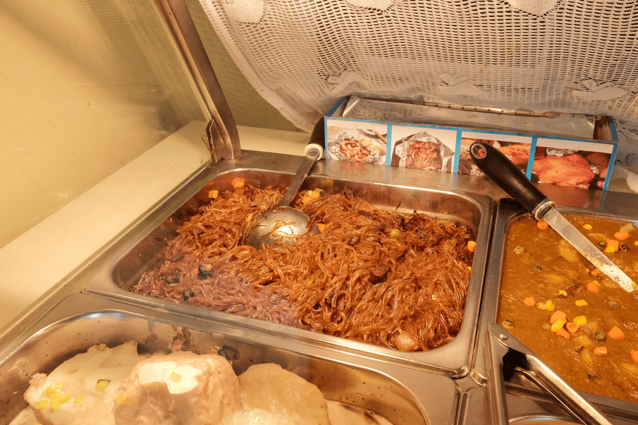 Brown chop suey fills a buffet tray in a warmer, with cooked taro in front and a curry to the right