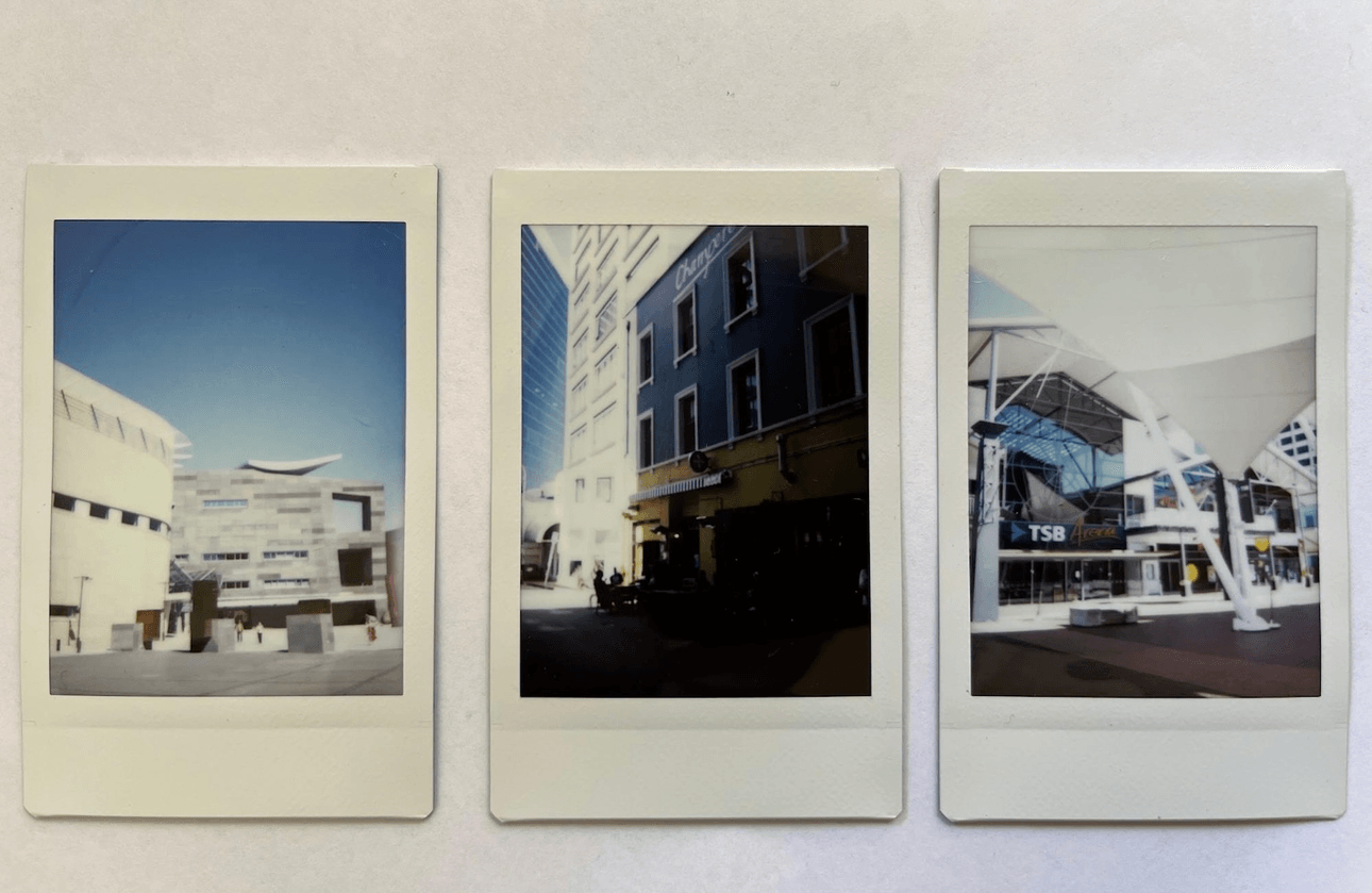 Three polaroids: the first shows the concrete courtyard of Te Papa, the second is a shadowed blue and yellow building, the last shows the entrance to TSB arena with white canopies overhead