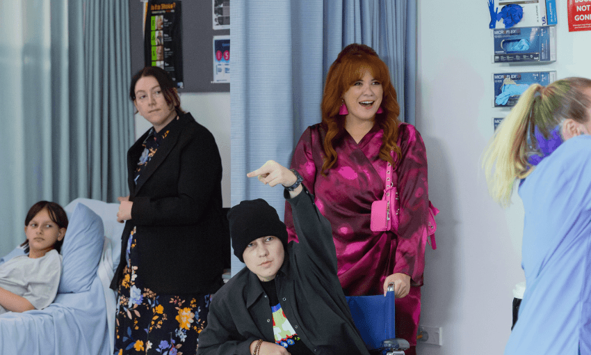 A hospital room scene with a teenage Brayden in a wheelchair with his mum Bethanaé, smiling standing behind him.