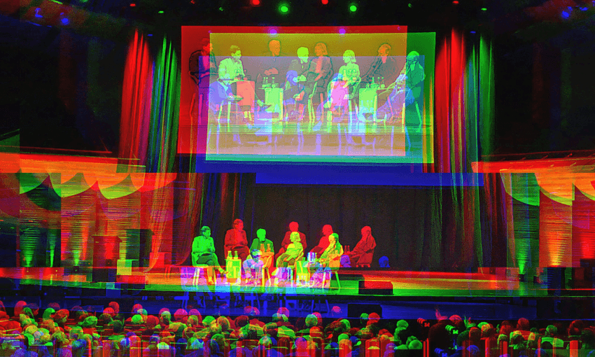 A fuzzy effect on an image of four panellists on stage at the Michael Fowler Centre in Wellington with a big screen behind them