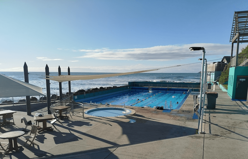 The st clair pool has concrete terraces and an orb of a small pool before the lane pool proper. pictured draped in shade, with the flat southern ocean beyond the wall