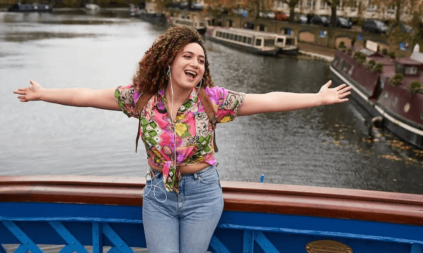 A woman with curly hair holds her arms open while listening to music on her ipod in Starstruck