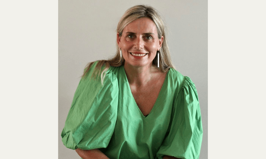 Sam Witters smiles at the camera in an emerald green blouse