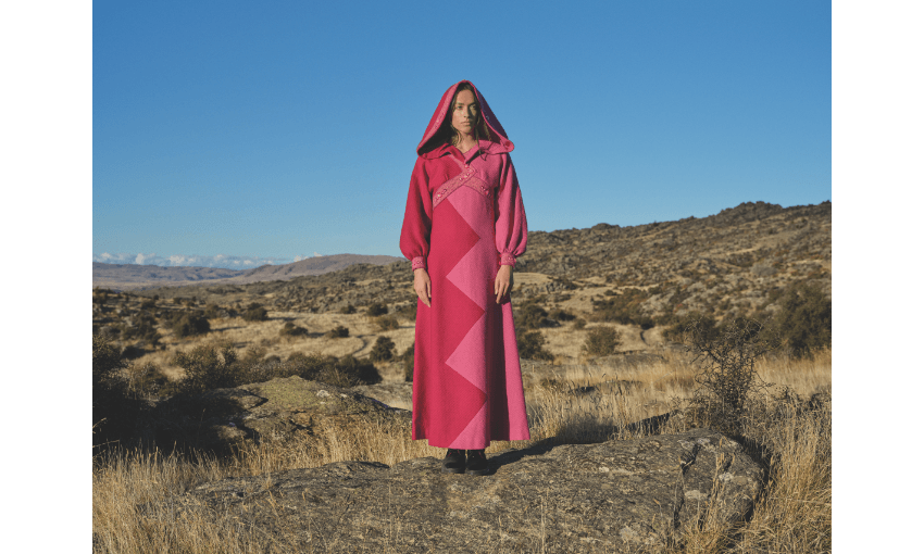 Photography of model Ngahuia Williams in bright pink garment, standing in Alexandra landscape.